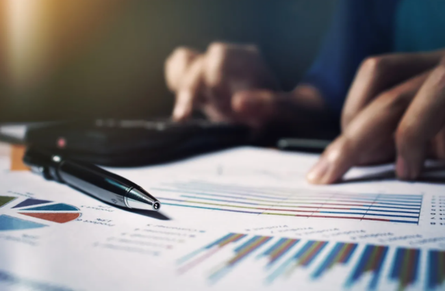 Person calculating data with graphs and pen.