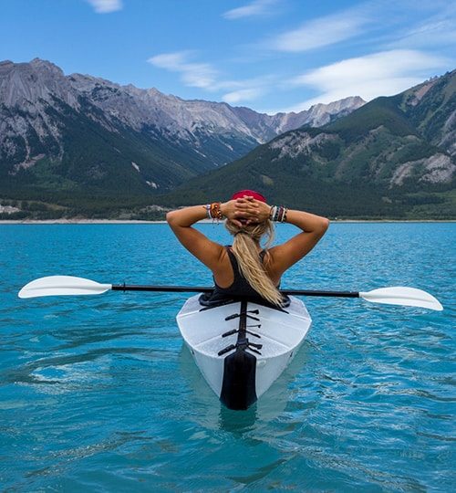Person kayaking on a turquoise lake.