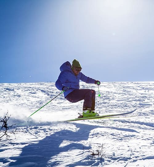 Skier navigating snowy slope under sun.