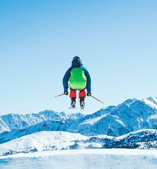 Skier jumping above snowy mountains.